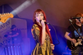 A woman with long red hair on stage singing into a microphone