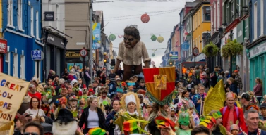 A 5-metre-high giant walking amongst a crowd of people in colourful clothes and costumes
