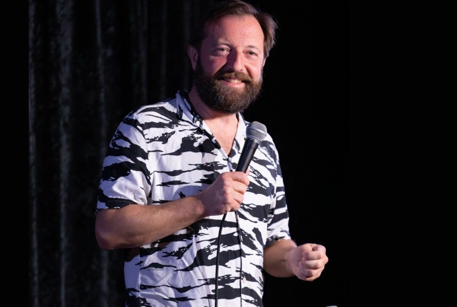 Andrew Maxwell performing standup against a black background. Photo cred: @craicdencomedy